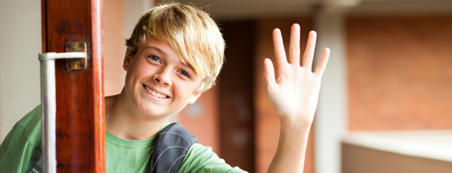 A young blond boy with green T-Shirt waving his hand